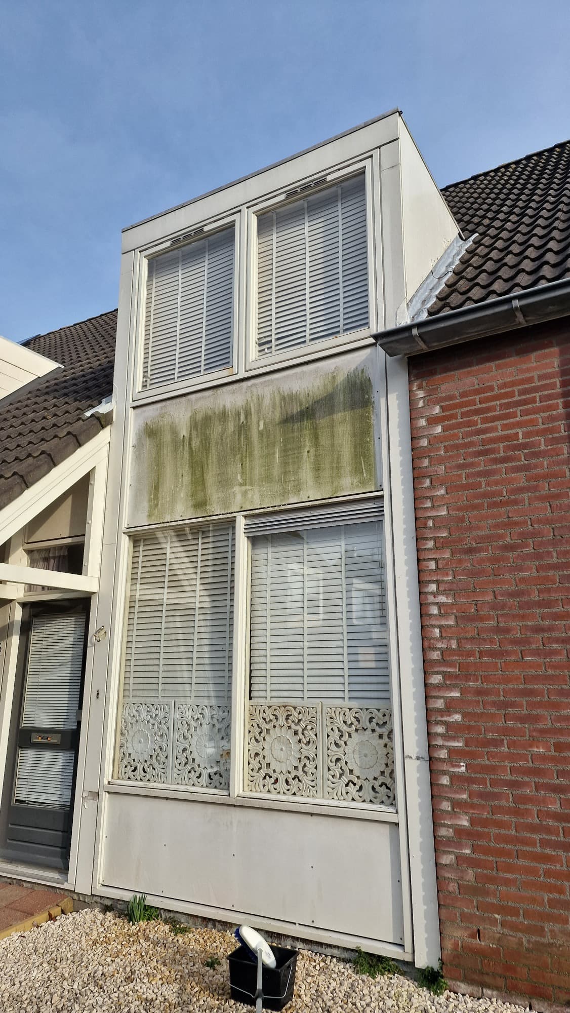Erkerpaneel met groene aanslag boven de ramen voor de gevelreiniging door Mooi Huis in Zeeland