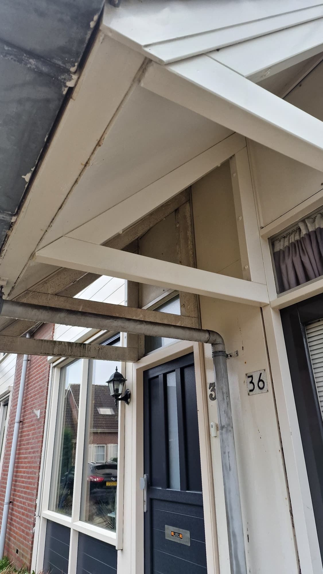 Luifel en dakrand met groene aanslag op de balken bij een entree, voor reiniging door Mooi Huis Zeeland